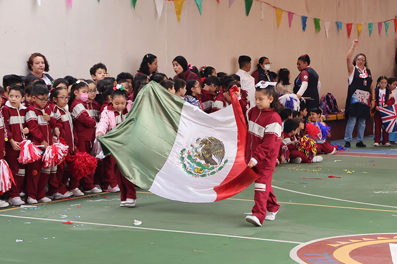 Estudiantes de nivel primaria del Colegio Oliverio Cromwell en la ceremonia cívica cargando la bandera de México